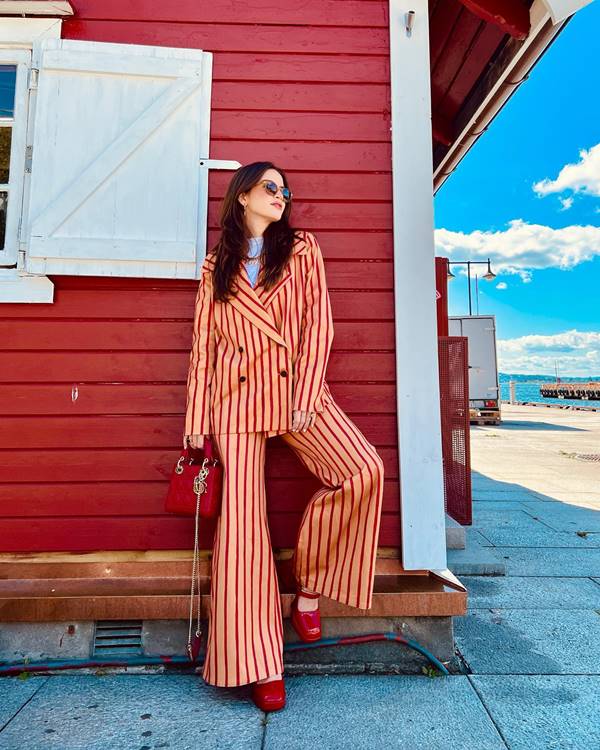 Mulher branca usa conjunto de blazer e calça listrado de branco e vermelho - Metrópoles 