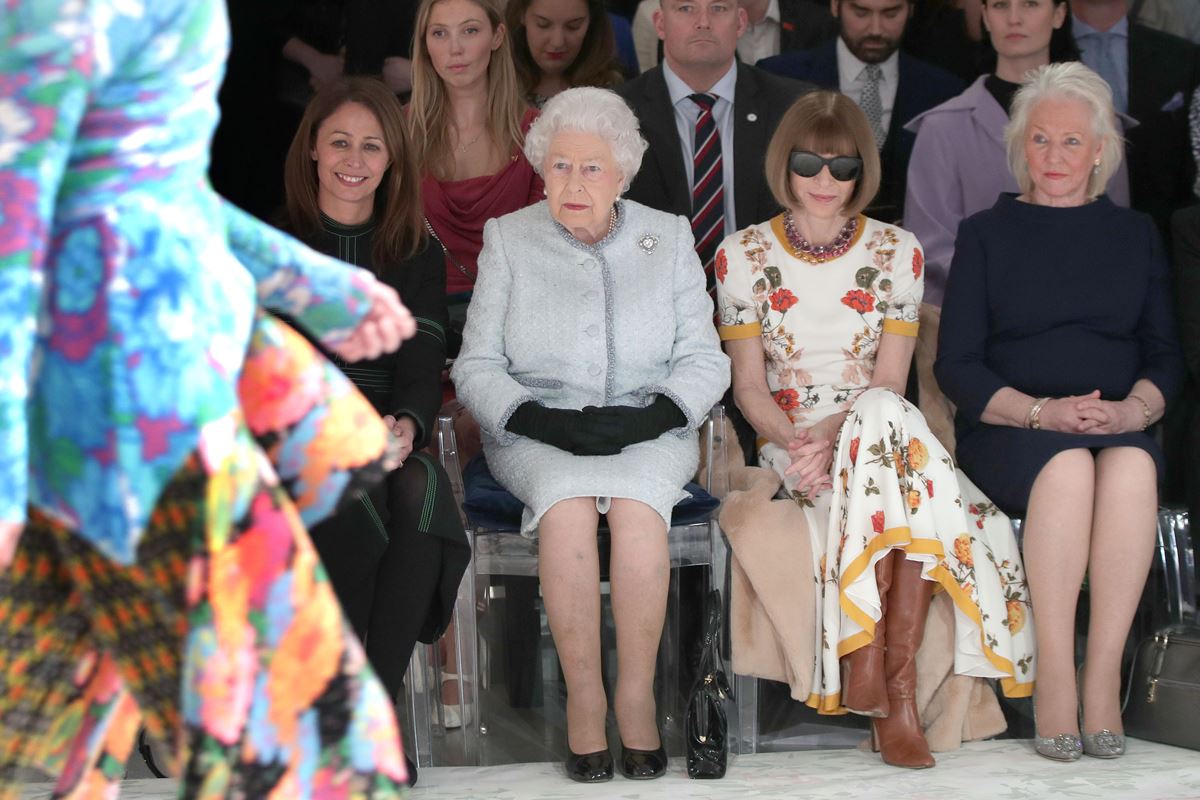 Foto colorida de quatro mulheres sentadas na primeira fila de um desfile - Metrópoles