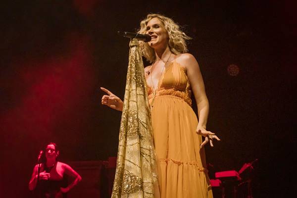 Mulher cantando em show com vestido longo e esvoaçante - Metrópoles