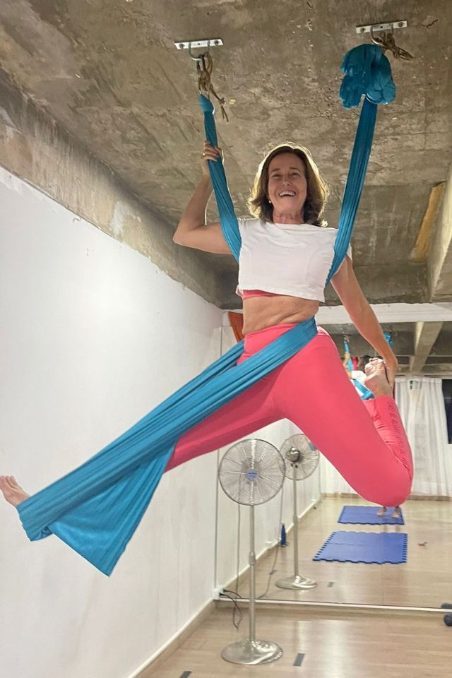 Mulher de 60 anos fazendo acrobacia circense em tecido no teto