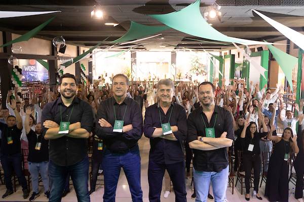 Fotografia colorida mostrando quatro homens de braços cruzados em cima de palco de costas para o público-Metrópoles