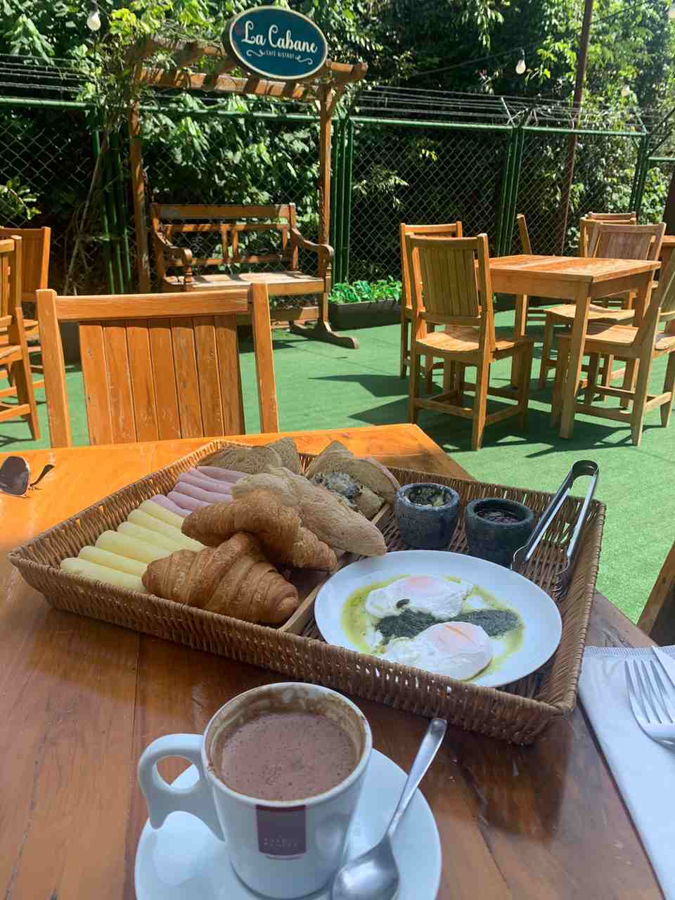 Na foto, uma mesa com itens de café da manhã e um jardim ao fundo - Metrópoles