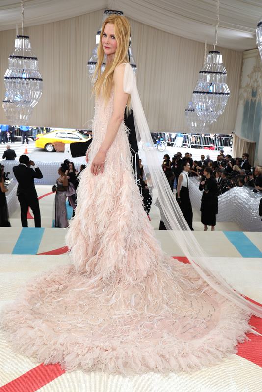 Na imagem com cor, uma mulher branca de cabelos ruivos claros usando um vestido com camadas em rosa claro - Metrópoles