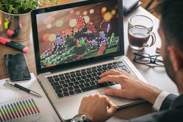 Fotografia colorida mostrando homem de terno jogando em cassino on-line pelo computador-Metrópoles