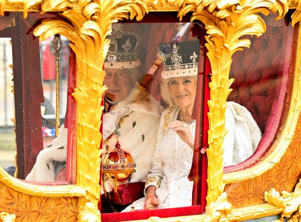 Rei e rainha se olham com coroas na cabeça - Metrópoles