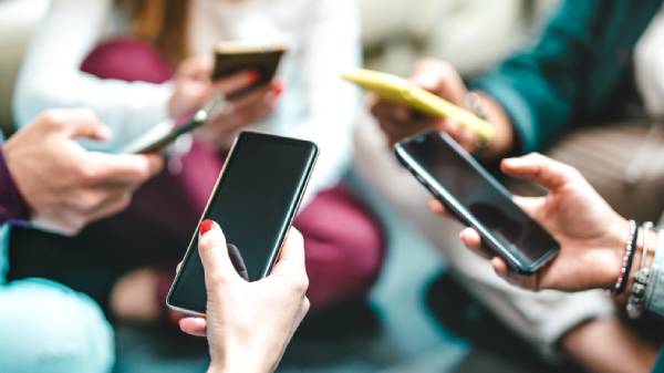 Fotografia colorida mostrando várias mãos segurando celular-Metrópoles