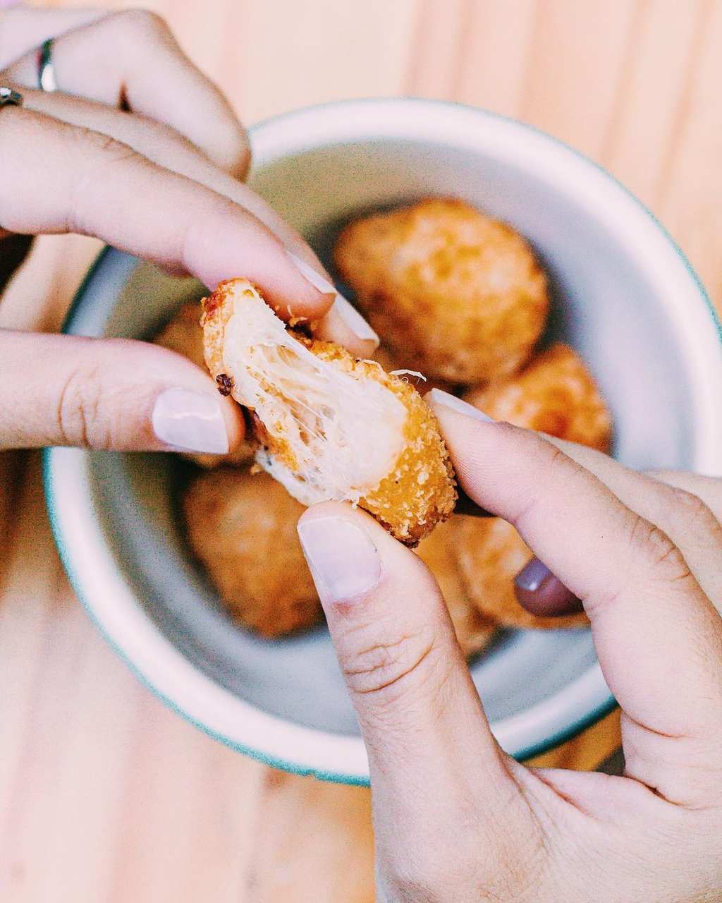 Na foto, um bowl com várias coxinhas e uma pessoa partindo uma ao meio - Metrópoles