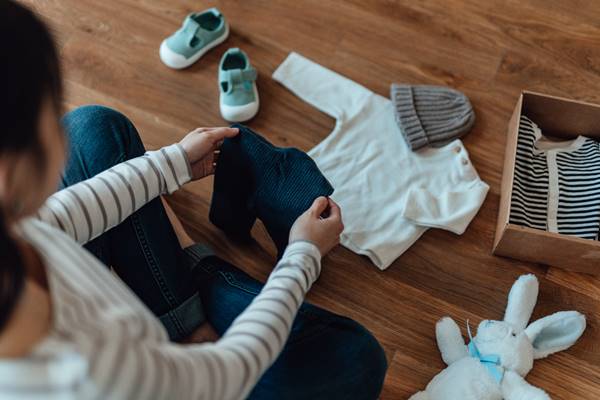 Mulher organiza roupa de bebê - Metrópoles