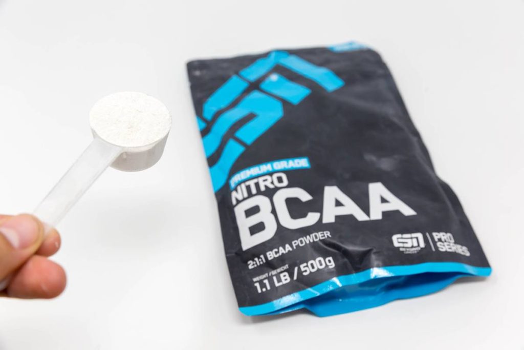 Produto escrito bcaa com saco preto e azul e scoop