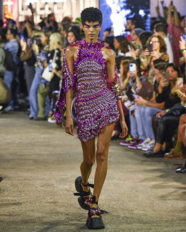 Modelo desfilando em passarela com vestido roxo - Metrópoles