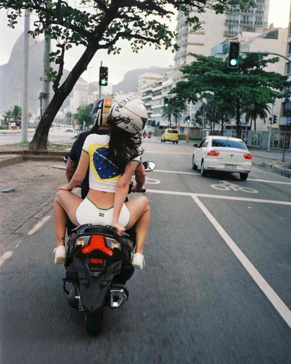 Na imagem com cor, uma mulher e um homem em uma moto andando na rua - Metrópoles