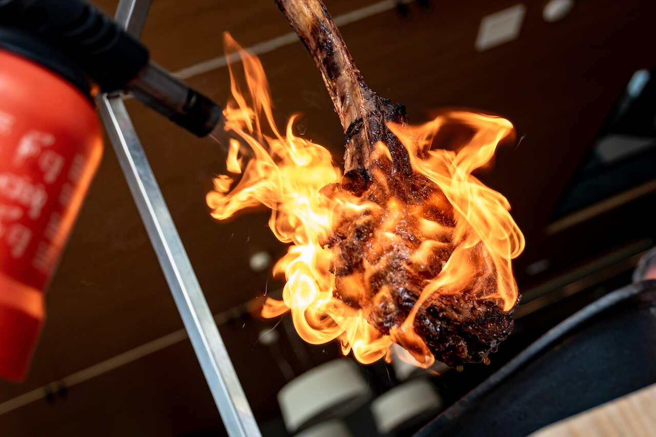 Na foto, uma carne pendurada sendo maçaricada - Metrópoles