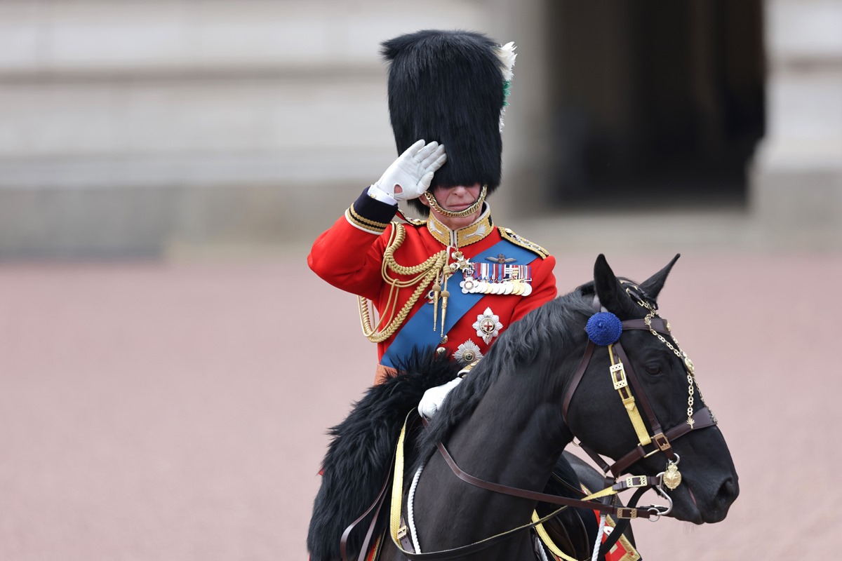 Foto colorida - Charles montado em um cavalo preto com roupa oficial vermelha 