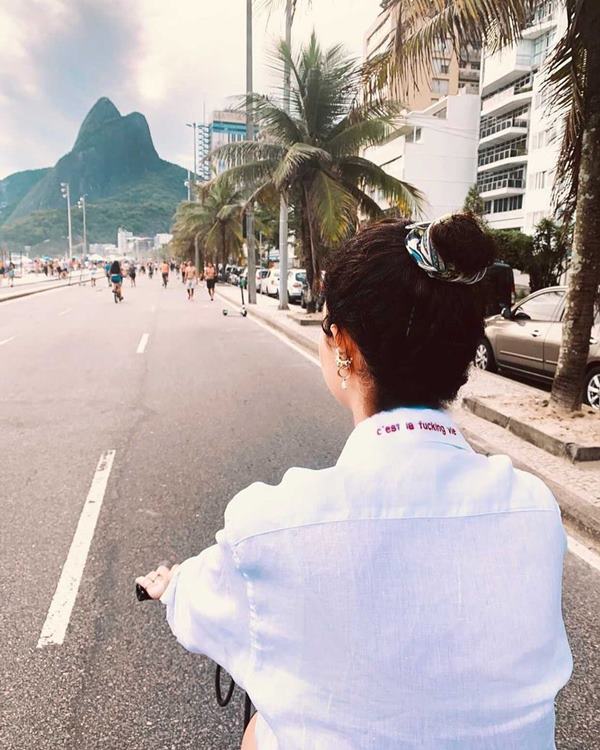 Mulher andando de bicicleta na rua com camisa social - Metrópoles