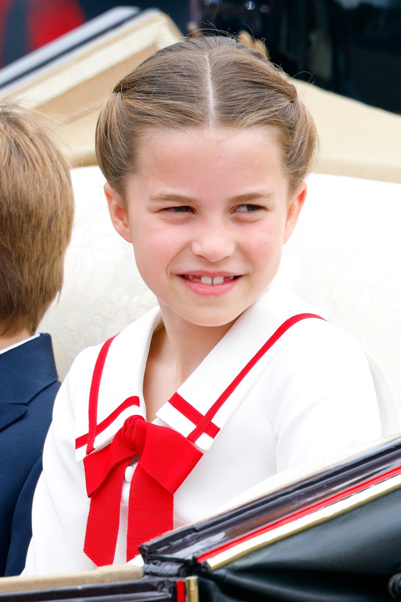 Foto colorida de menina, branca e loira, com um penteado no cabelo. Ela usa uma roupa branca com detalhes na cor vermelha - Metrópoles