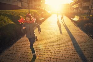 Foto colorida de criança correndo de agasalho no frio