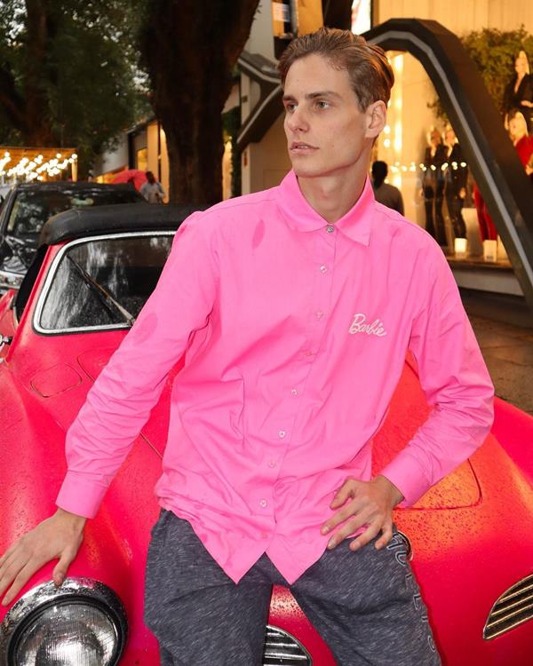 Homem posando em capô de carro cor de rosa - Metrópoles