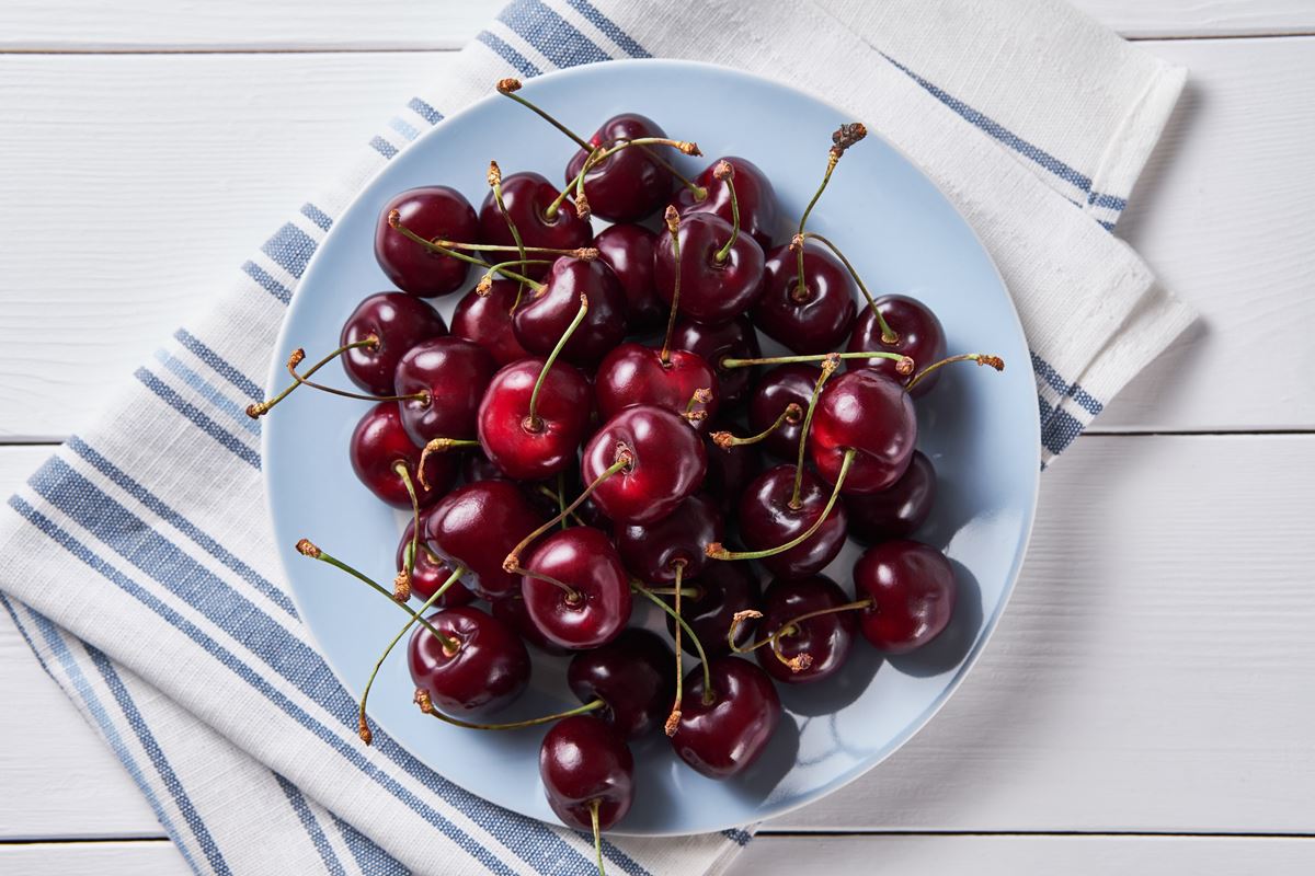 Foto colorida de prato branco com cerejas dentro - Metrópoles