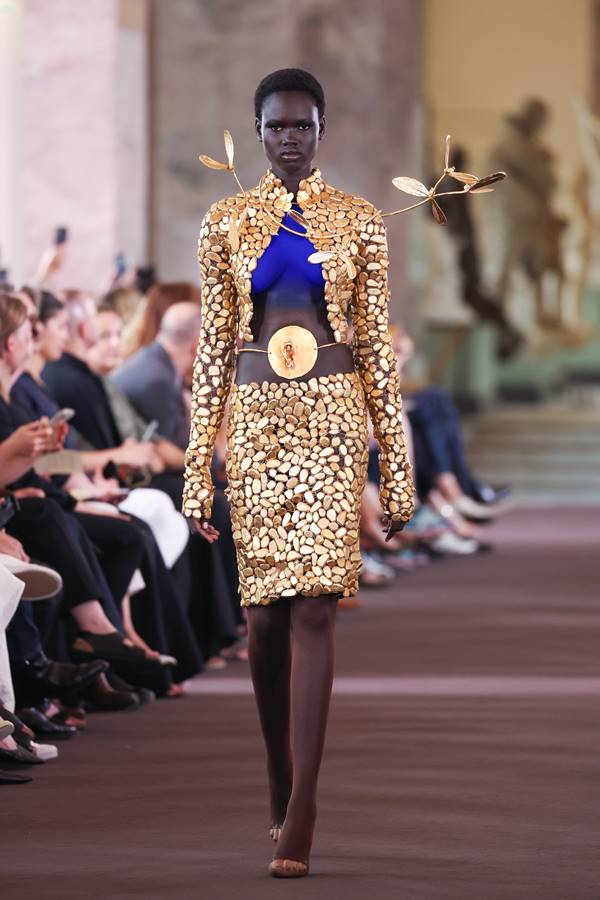 Na passarela da Schiaparelli, modelo usa look dourado com aplicações e tinta azul no colo - Metrópoles