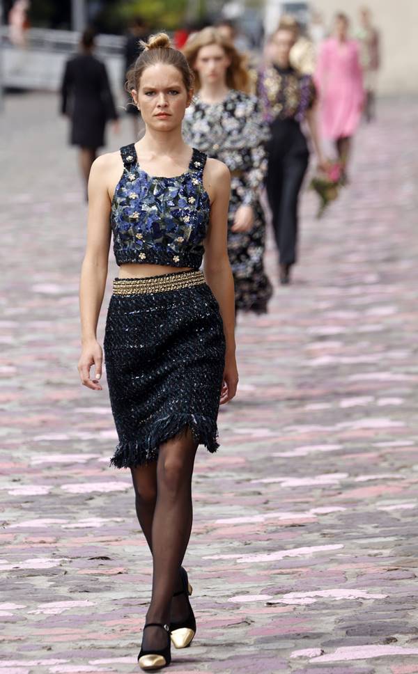 Na passarela, modelo usa cropped azul com brilho e saia de tweed preta, além de meia-calça fina e sapato Mary Jane - Metrópoles