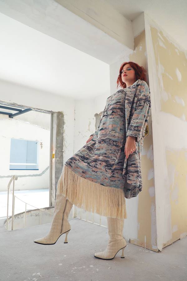 Em cenário de construção residencial, mulher branca e ruiva usa vestido cinza estampado em jacquard com babado bege na barra - Metrópoles