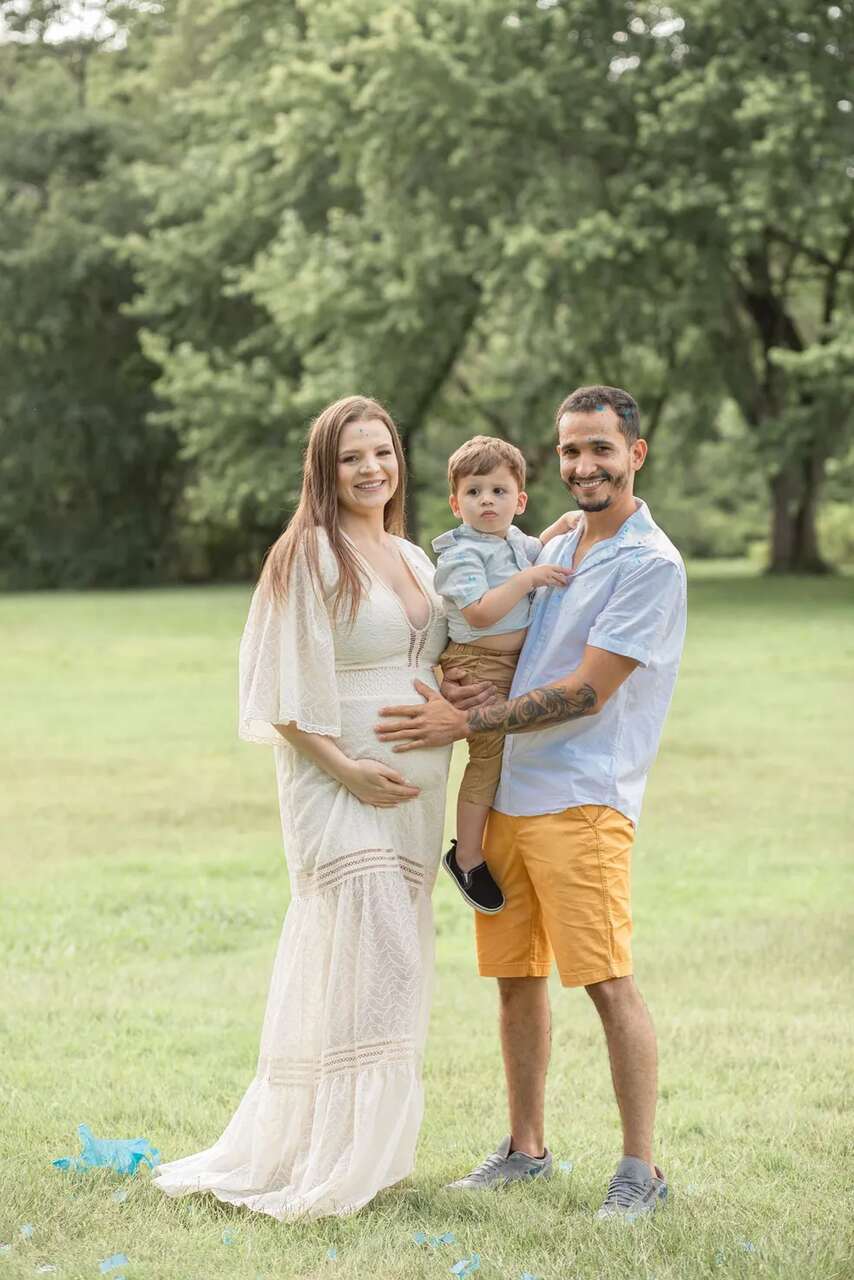 Na foto, uma mulher grávida posa para foto ao lado de um homem e uma criança - Metrópoles