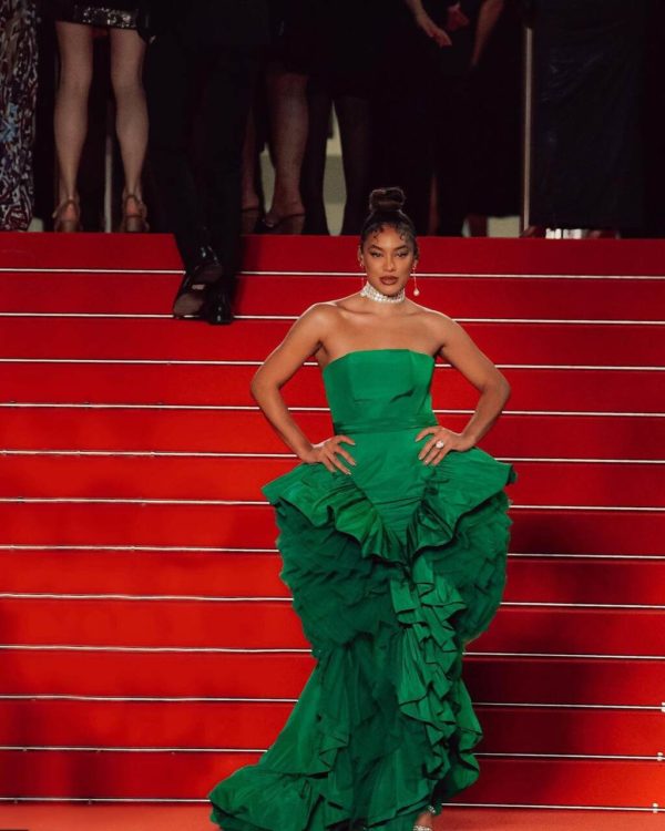 Na imagem com cor, uma mulher negra em uma escada usando um vestido verde - Metrópoles