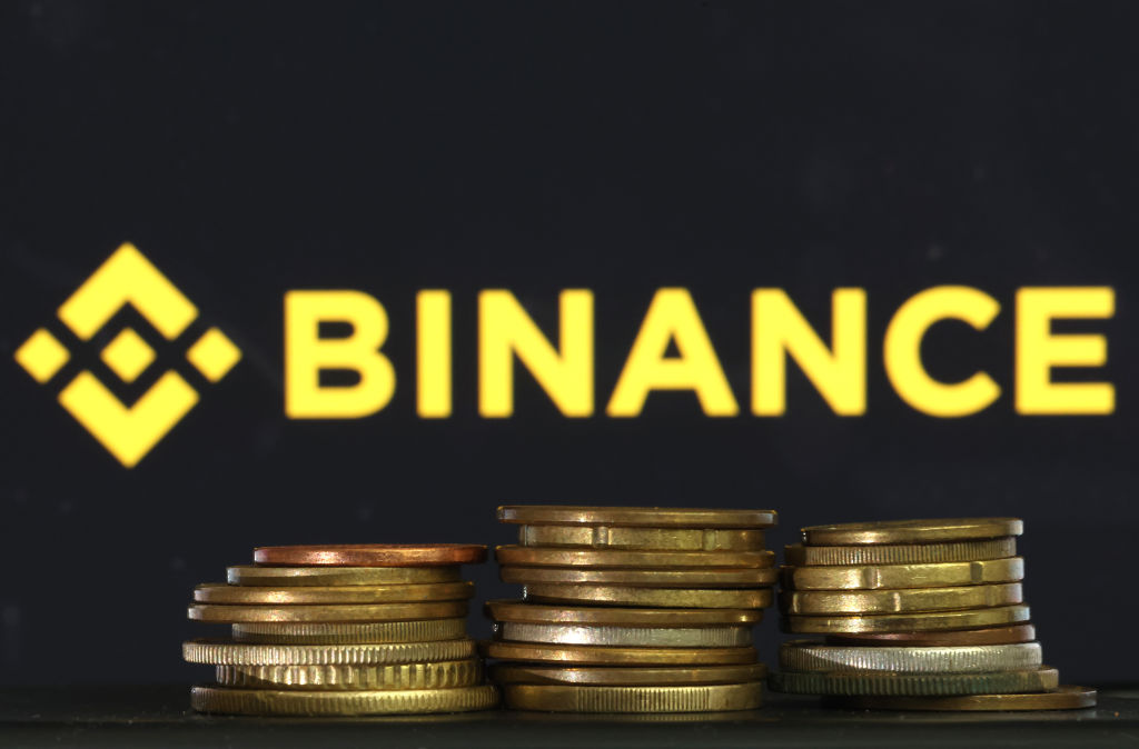 Pilhas de moedas com a logo da Binance ao fundo