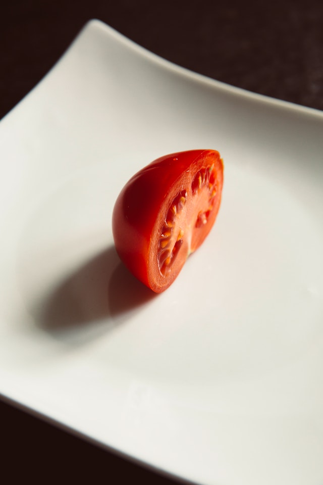 Fatia de meio tomate cortada em um prato branco - Metrópoles