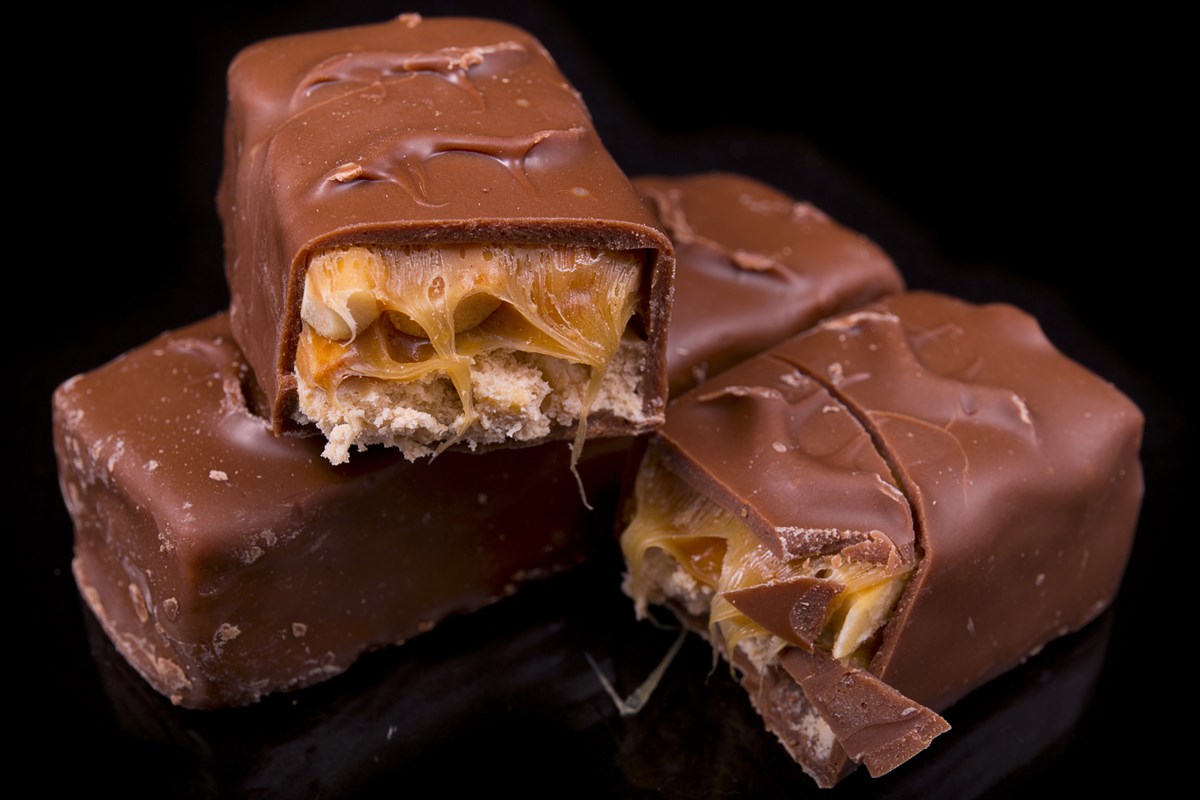 Foto colorida de barras de chocolate com recheio de caramelo e amendoim - Metrópoles