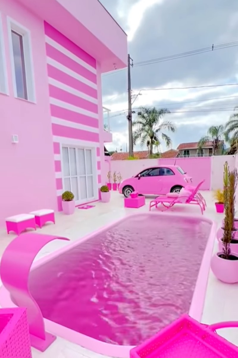 Foto colorida de casa, carro, piscina e itens decorativos cor-de-rosa - Metrópoles