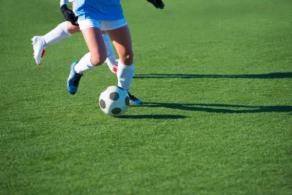 Fotografia colorida mostrando duas jogadoras disputando bola em gramado de futebol-Metrópoles