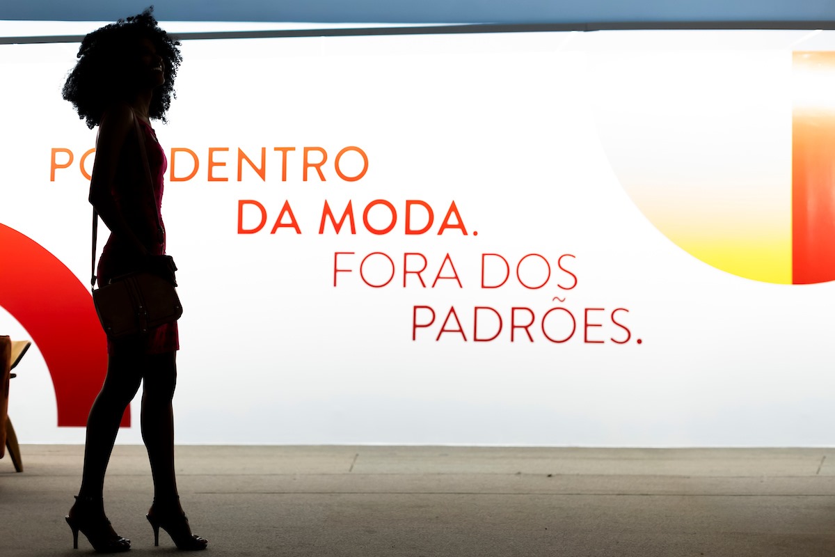 Painel em branco com a escrita em vermelho "por dentro da moda, fora dos padrões" - Metrópoles