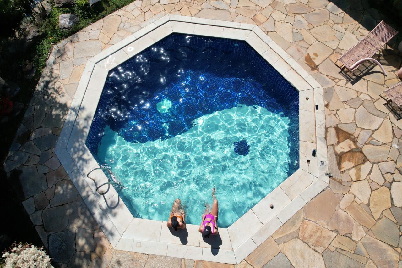 Foto colorida. Imagem mostra a piscina vista da parte de cima. Duas mulheres estão dentro dela - Metrópoles