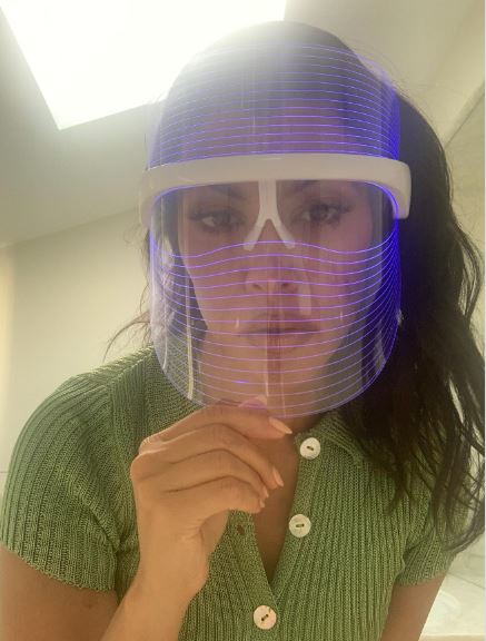 Foto colorida. Kourtney Kardashian possui cabelos pretos, e lisos. Ela está usando uma máscara de LED para tratamento da pele - Metrópoles