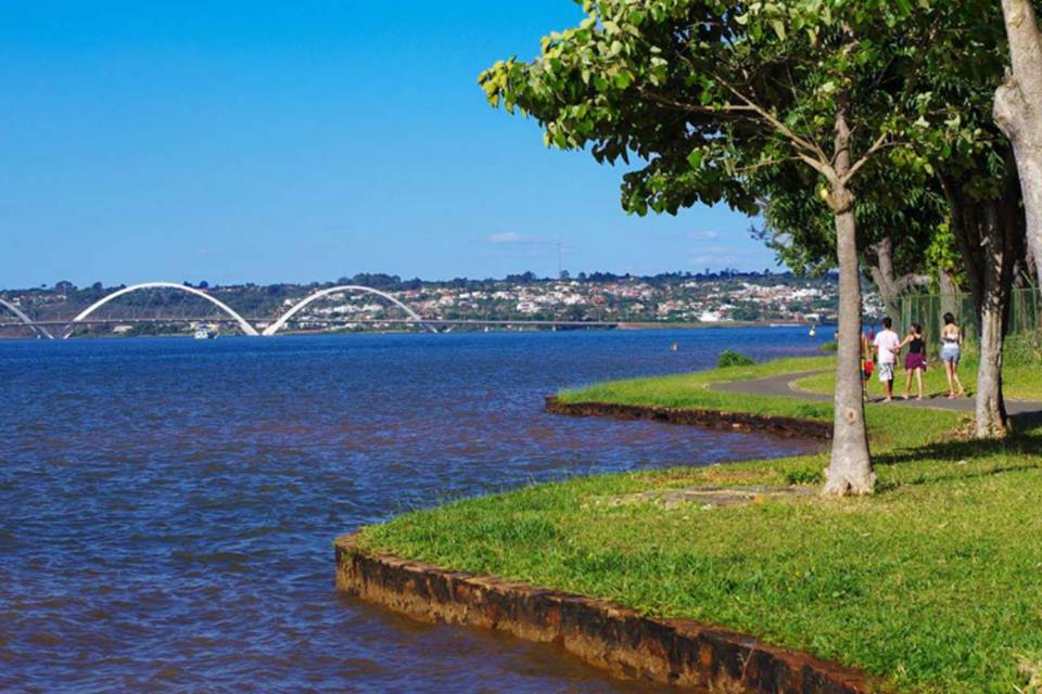 Na foto, um lago, uma área verde e várias árvores na beira do lago - Metrópoles