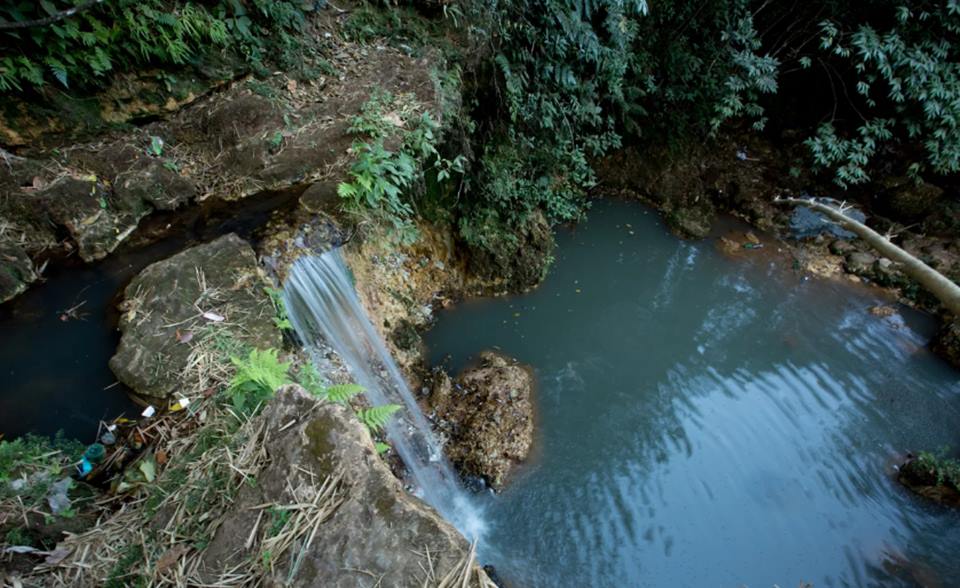 Na foto, uma cachoeira e um lago azul rodeado de pedras e plantas - Metrópoles