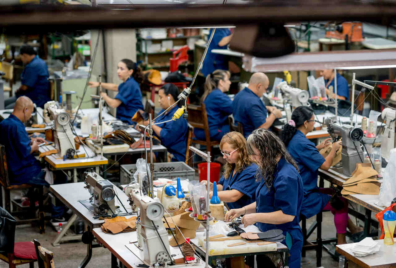 Na imagem com cor, uma sala cheia de costureiras trabalhando - Metrópoles