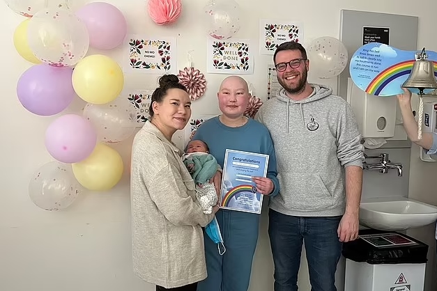 Foto colorida de família com mãe, pai, menina adolescente e bebê em frente a balões - Metrópoles