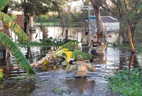 Policiais caminham em rio no Pantanal