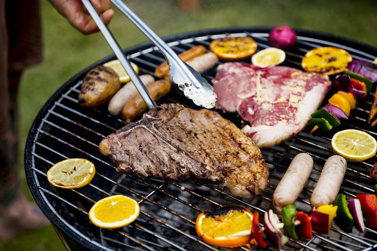 Foto colorida de grelha com frutas e duas fatias de carne, sendo uma assada e outra crua - Metrópoles