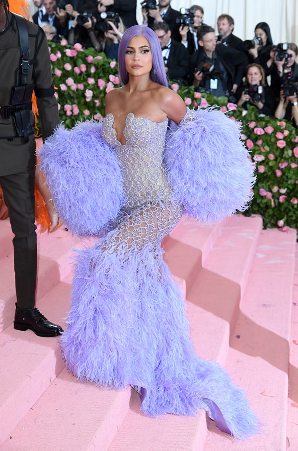 Mulher subindo a escadaria de um evento. Ela está com um vestido roxo de mangas bufantes - Metrópoles