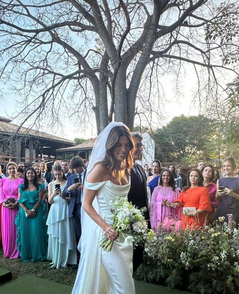 Jovem noiva entrando no altar em casamento com pessoas ao fundo. Ela está acompanhada de um homem - Metrópoles