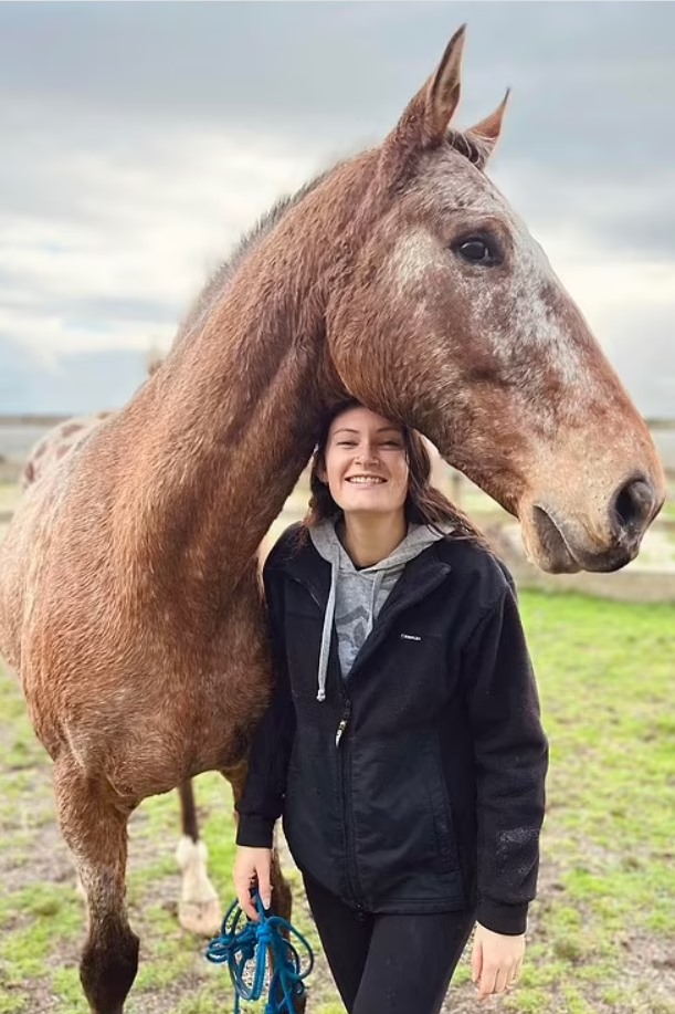 Foto colorida de mulher sorrindo segurando cavalo - Metrópoles