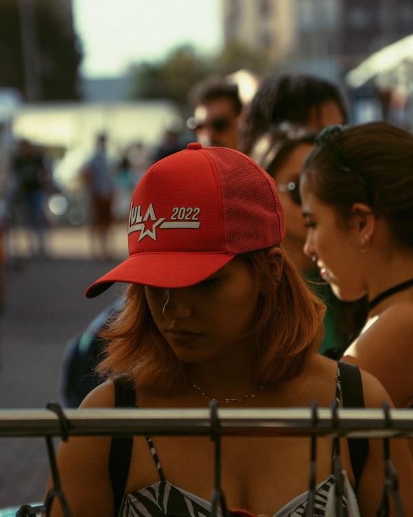 Mulher com boné vermelho olhando uma arara de roupas em feira - Metrópoles