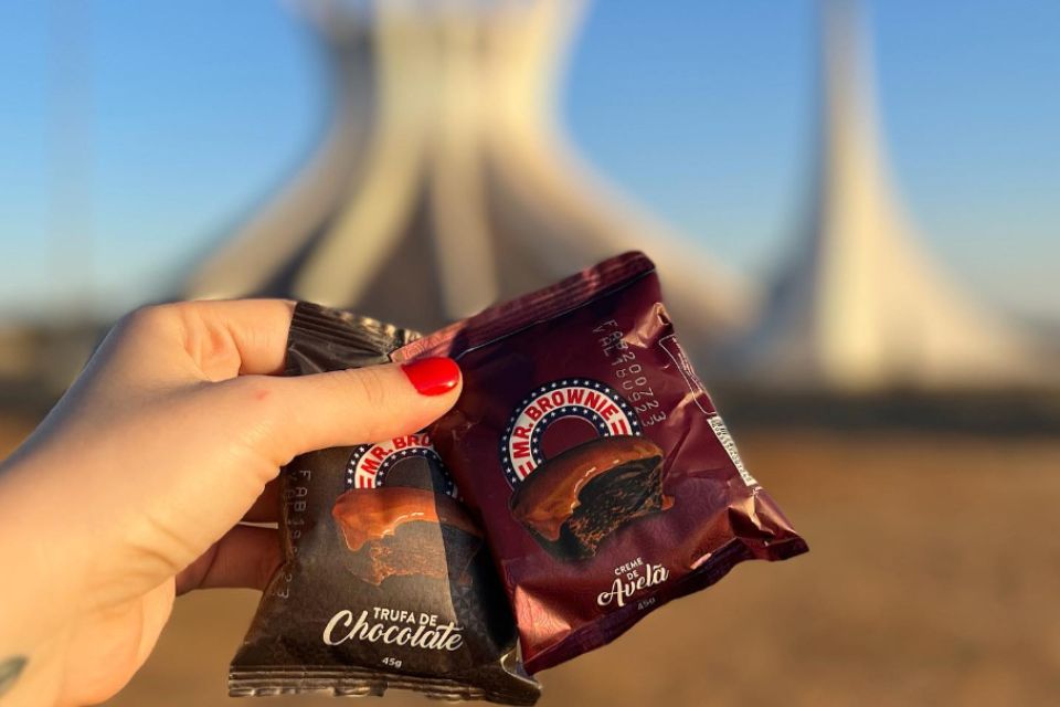 Foto colorida de um brownie de chocolate em frente a Catedral - Metrópoles