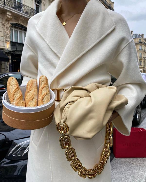 Homem parado na rua segurando uma cesta de pães com uma das mãos e uma bolsa com a outra - Metrópoles