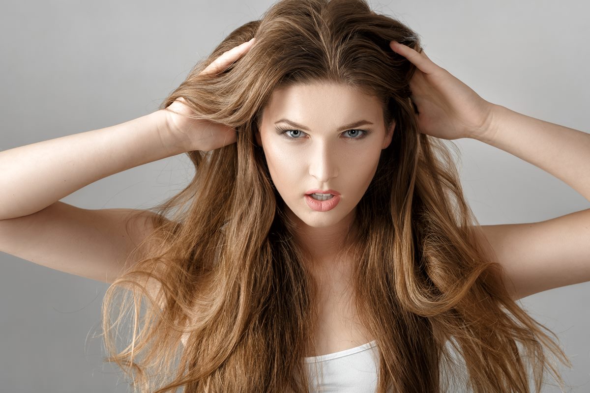 Foto colorida de mulher branca, com as mãos no cabelo longo - Metrópoles