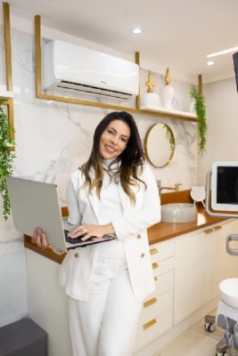 foto colorida de uma mulher segurando um notebook em um consultório de dentista - Metrópoles