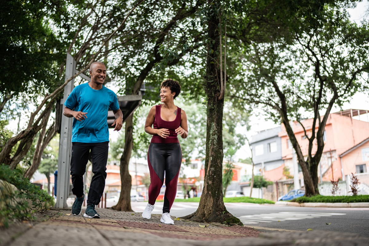 Foto colorida. Um homem e uma mulher, ambos negros, estão praticando corrida ao ar livre - Metrópoles